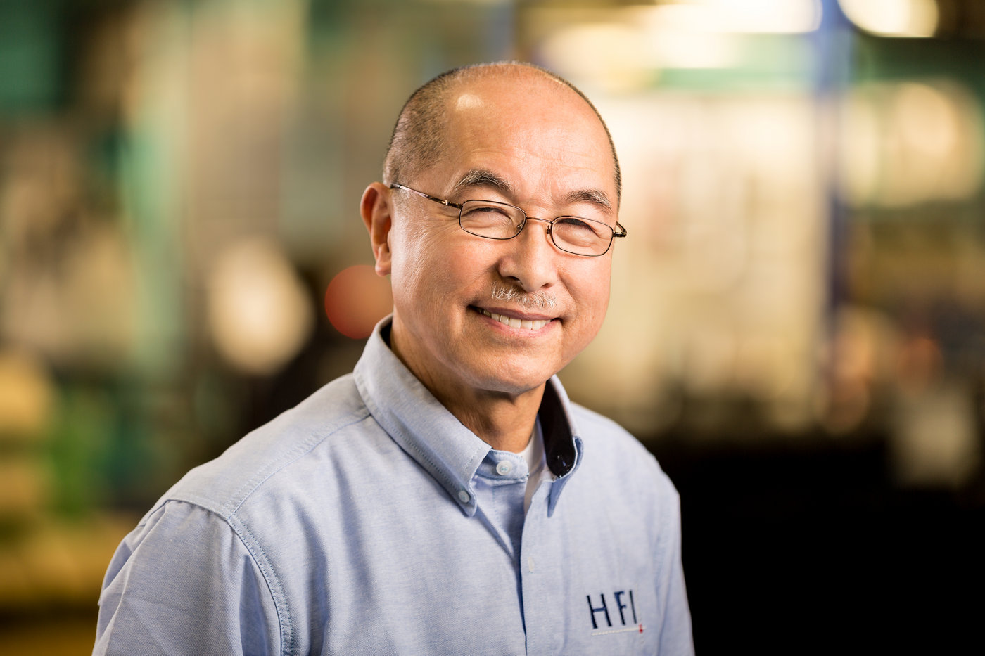 a man poses for a headshot in an automotive factory while wearing his company's logo on his shirt to demonstrate one of the tips for great branding photos