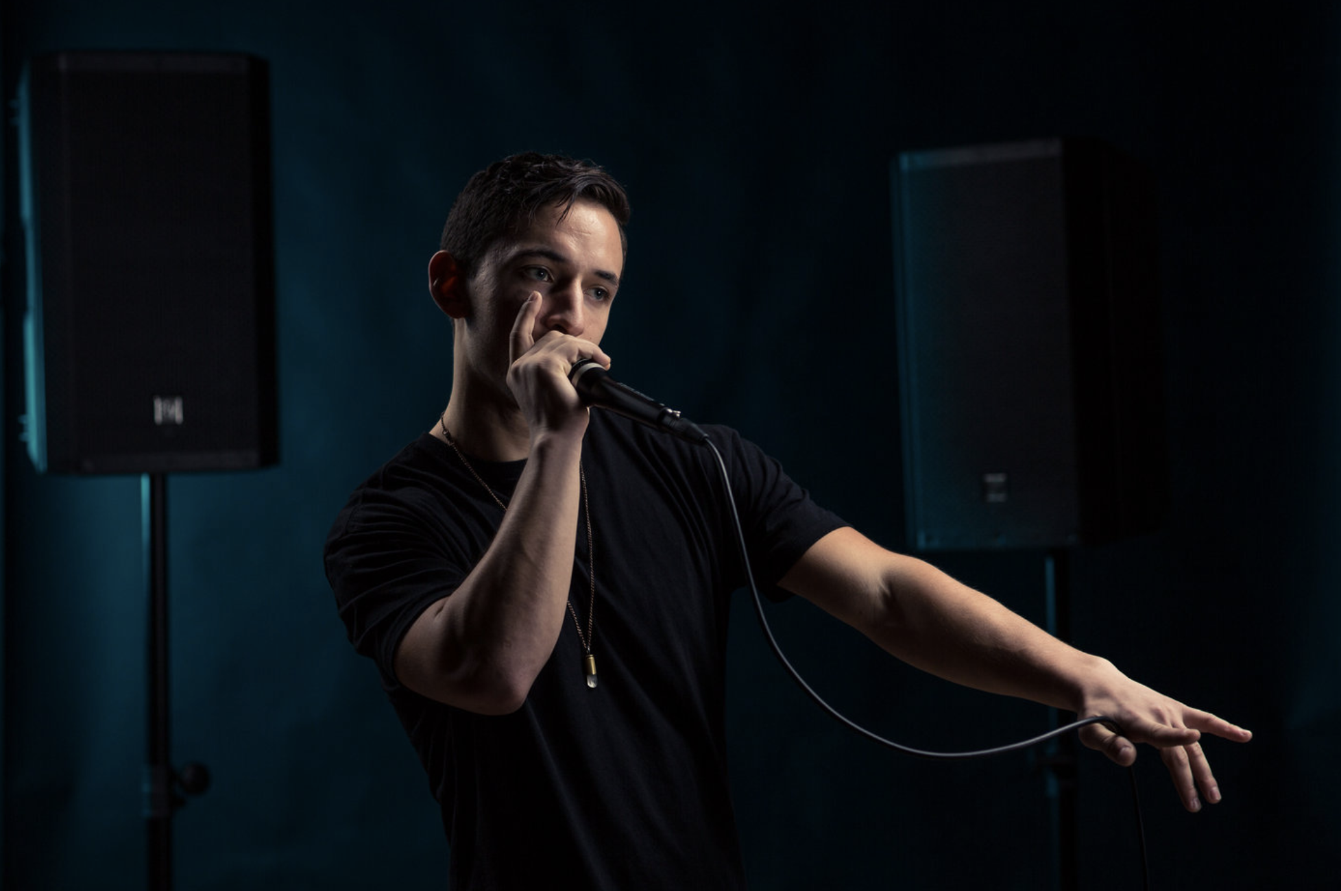 a beat boxer dances and beats with a microphone in his hand and speakers in the background