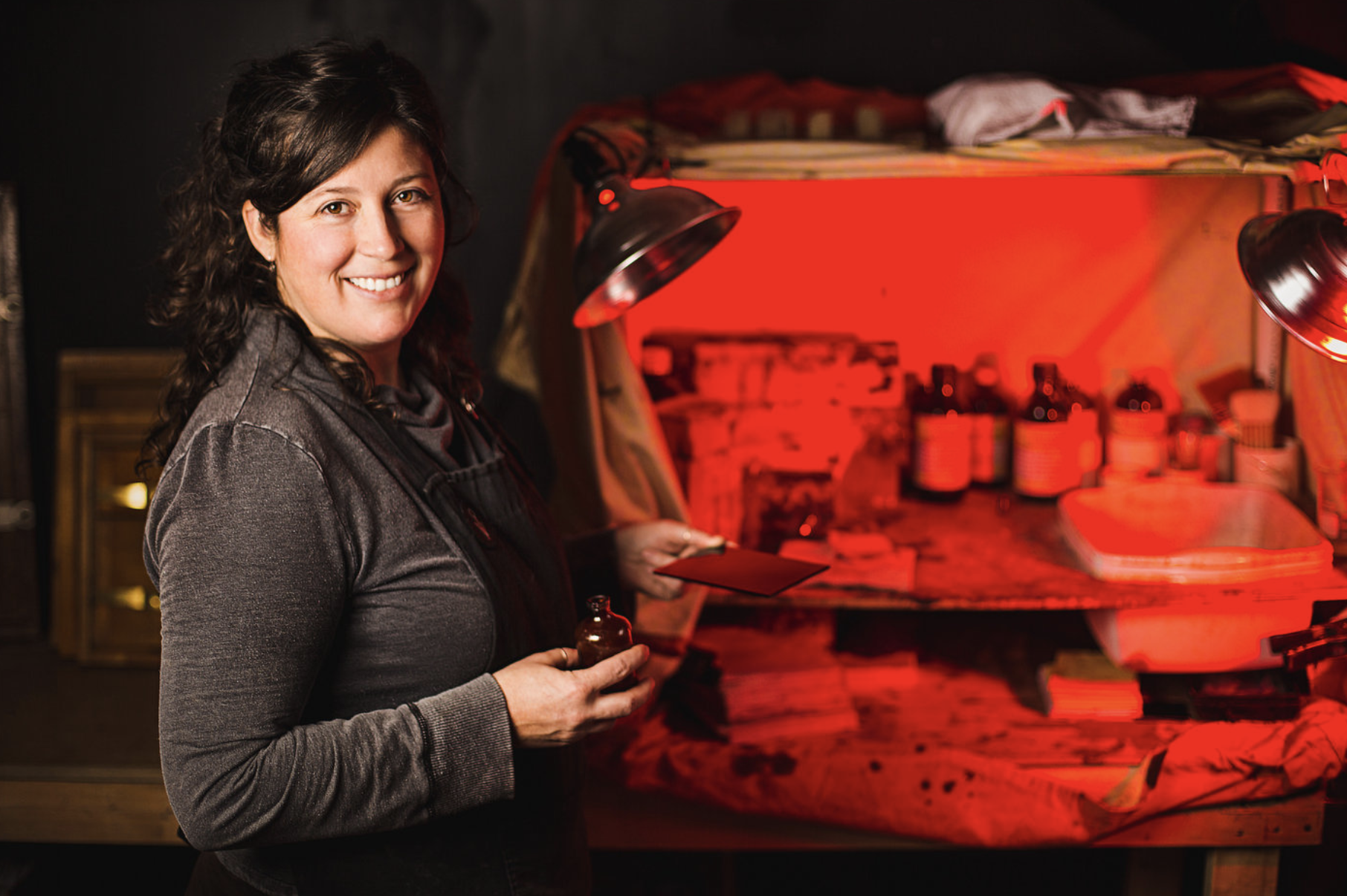 a female artist poses with her materials in front of a dark room set up to demonstrate one of the tips for great branding photos